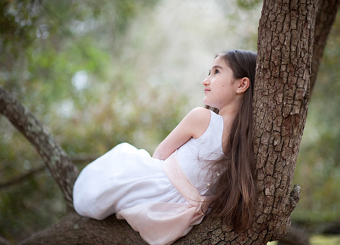 The girl is sitting on the old oak tree branch