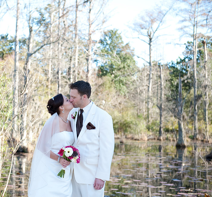 The couple is kissing in cypress gardens in Charleston sc